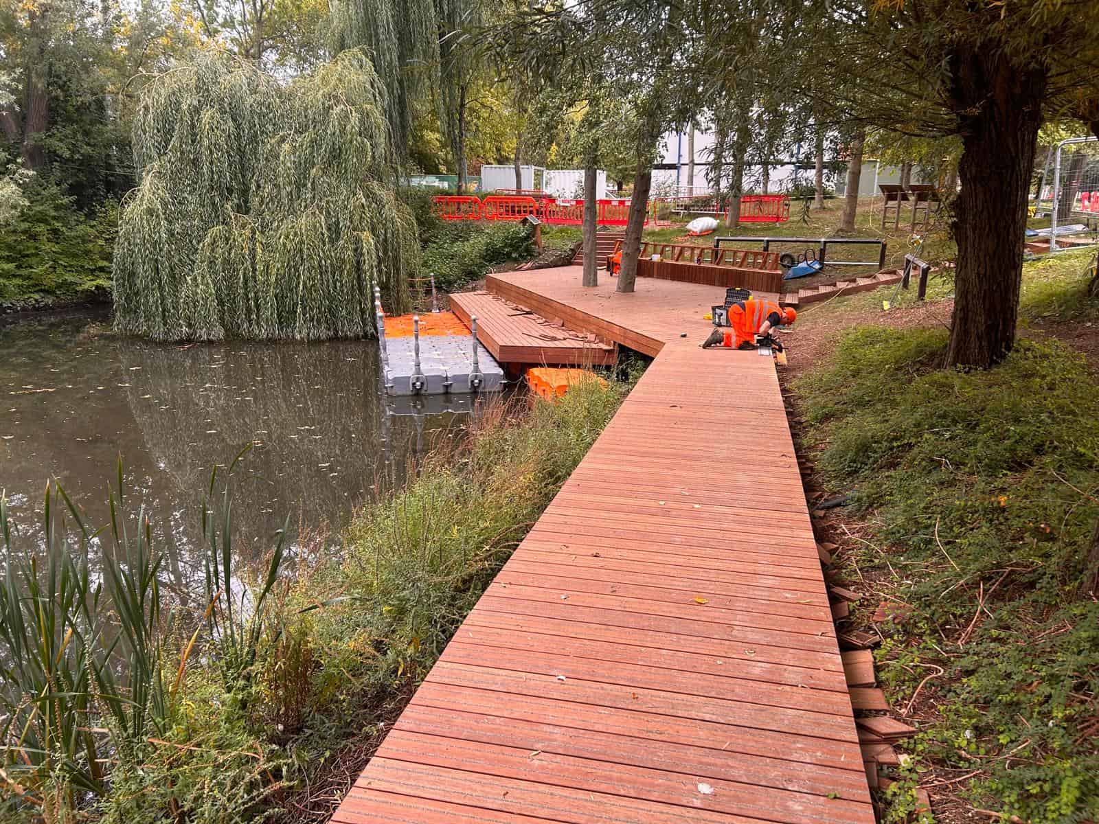 The boardwalk pathway leading to the bench area and lower platform. A Modular Cube working platform with rope handrails sits in the pond near the lower platform.