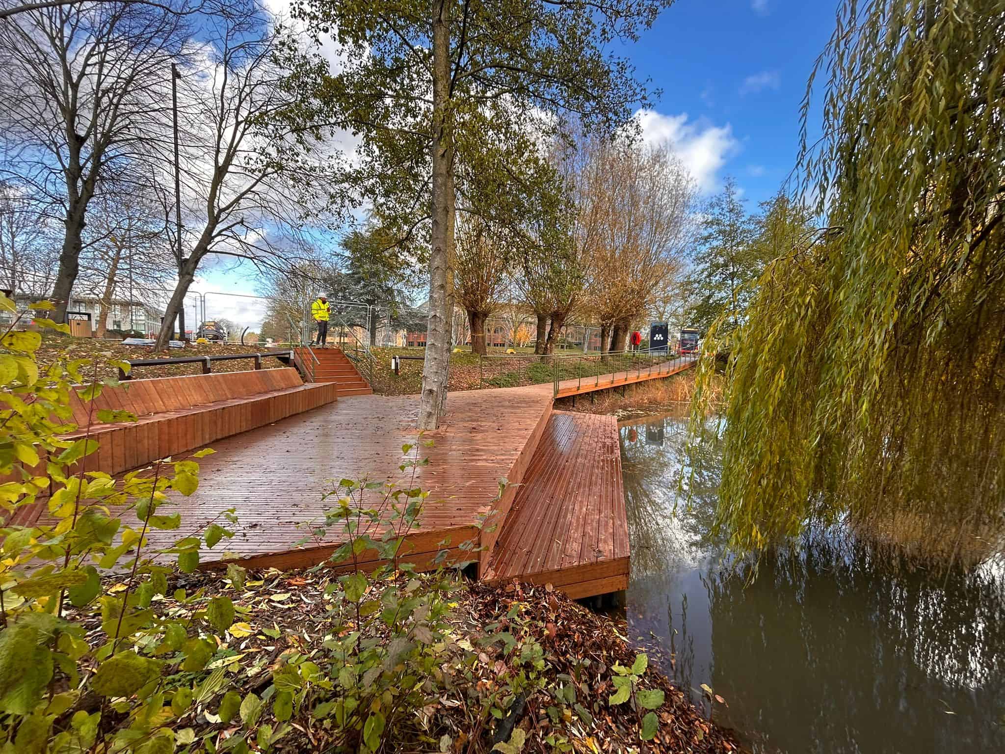 The completed boardwalk, with custom bench, lower pondside platform and custom handrails and stairs, surrounded by trees